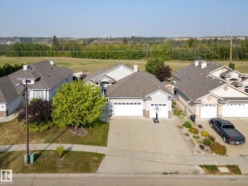 Ranch-style residence featuring a double-car garage, concrete driveway, and a landscaped front yard with mature trees - 34 Valleyview Ridge, Fort Saskatchewan, AB - Outdoor With View
