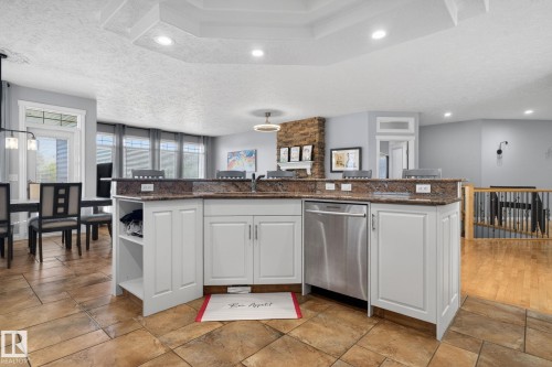 Kitchen island featuring white cabinetry, a built-in stainless steel dishwasher, and a stone-finish countertop - 34 Valleyview Ridge, Fort Saskatchewan, AB - Indoor Photo Showing Kitchen