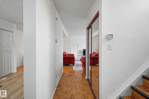 The property features wood parquet flooring, a white interior door, and a white staircase with wood treads - 6F Castle Terrace, Edmonton, AB - Indoor Photo Showing Other Room