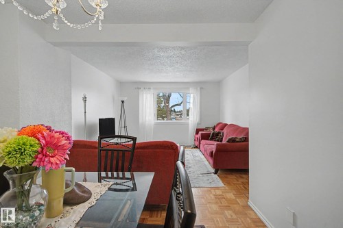 The property features a living area with light-colored walls, a window providing natural light, and parquet flooring - 6F Castle Terrace, Edmonton, AB - Indoor