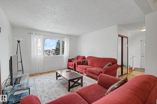 The living area features light wood flooring, white walls, and a large window with white curtains - 6F Castle Terrace, Edmonton, AB - Indoor Photo Showing Living Room