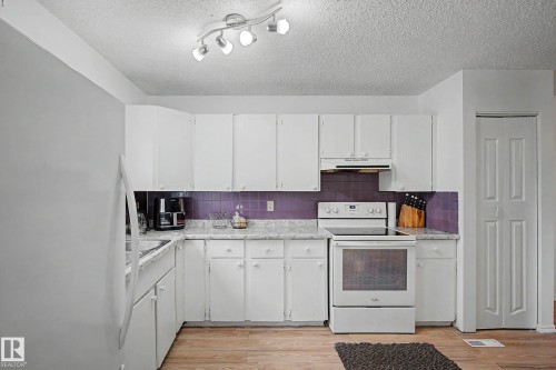 The kitchen features white cabinetry, a purple tiled backsplash, and a white oven - 6F Castle Terrace, Edmonton, AB - Indoor Photo Showing Kitchen