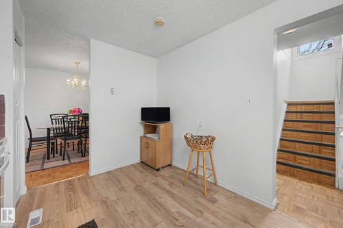 The property features light wood flooring and white walls throughout, with a clear view into a dining area that includes a chandelier - 6F Castle Terrace, Edmonton, AB - Indoor Photo Showing Other Room