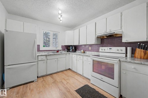 The kitchen features white cabinetry, a white refrigerator, and a white electric range with an overhead hood - 6F Castle Terrace, Edmonton, AB - Indoor Photo Showing Kitchen