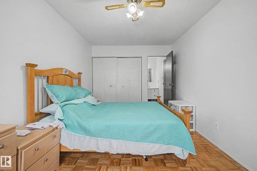 This room features white walls, parquet wood flooring, a ceiling fan, and white bi-fold closet doors - 6F Castle Terrace, Edmonton, AB - Indoor Photo Showing Bedroom
