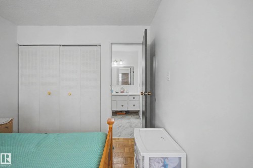 The room features white walls, a parquet wood floor, and louvered bi-fold closet doors with gold-toned knobs - 6F Castle Terrace, Edmonton, AB - Indoor Photo Showing Bedroom