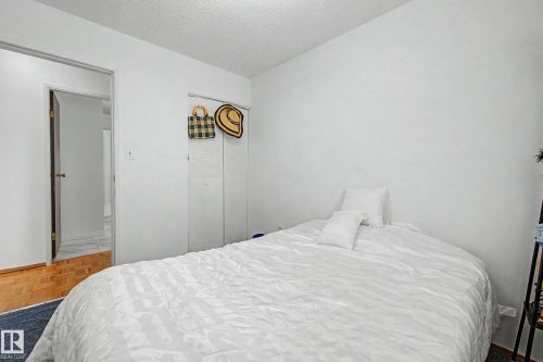 Bedroom featuring white walls, a white textured ceiling, and a doorway leading to an area with hardwood flooring - 6F Castle Terrace, Edmonton, AB - Indoor Photo Showing Bedroom