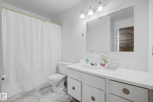 Bathroom featuring a vanity with a white countertop and an integrated sink, a large mirror, and a toilet - 6F Castle Terrace, Edmonton, AB - Indoor Photo Showing Bathroom