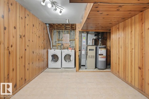 The property features a laundry area with a washer and dryer, tiled flooring, and wood paneling on the walls and ceiling - 6F Castle Terrace, Edmonton, AB - Indoor Photo Showing Laundry Room