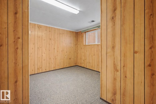 The room features wood paneling, a gray patterned carpet, and a window with a valance - 6F Castle Terrace, Edmonton, AB - Indoor Photo Showing Other Room