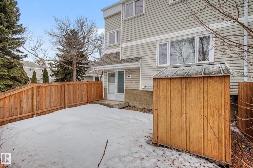 Exterior view of the property with light-colored siding, featuring a wood fence, an outdoor storage shed, and a main entry door with a storm door - 6F Castle Terrace, Edmonton, AB - Outdoor