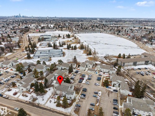 Aerial view of the property and its surrounding area, featuring paved parking areas, trees, and buildings with pitched roofs - 6F Castle Terrace, Edmonton, AB - Outdoor With View