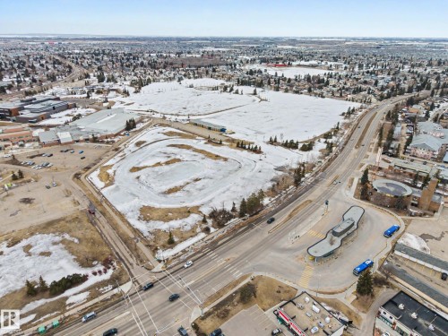 Aerial view showcasing the surrounding neighborhood, including a building with a large parking lot, a wide road with vehicles, and expansive fields - 6F Castle Terrace, Edmonton, AB - Outdoor With View