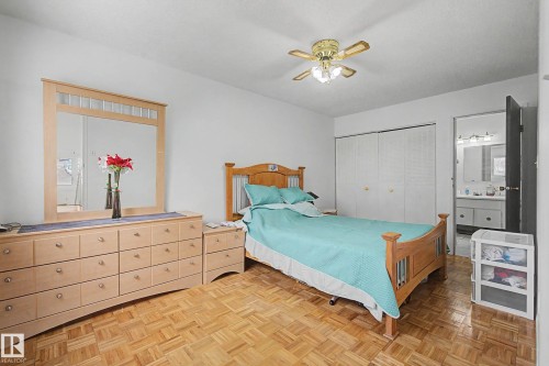 Bedroom featuring parquet flooring, a ceiling fan with integrated lighting, and a closet with bifold doors - 6F Castle Terrace, Edmonton, AB - Indoor Photo Showing Bedroom