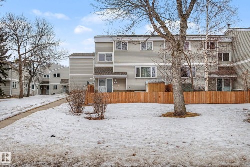 The property features a multi-level exterior with siding, a private fenced yard, and surrounding mature trees - 6F Castle Terrace, Edmonton, AB - Outdoor