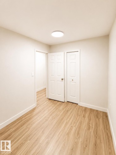 Recessed lighting, wood-finish flooring, white paneled doors, and neutral wall finishes - 13833 24 Street Nw, Edmonton, AB - Indoor Photo Showing Other Room