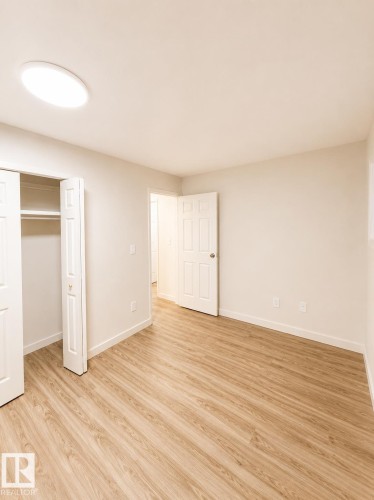 Light wood-finish flooring with crisp white baseboards and a ceiling-mounted light fixture - 13833 24 Street Nw, Edmonton, AB - Indoor Photo Showing Other Room