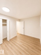 Light wood-finish flooring with crisp white baseboards and a ceiling-mounted light fixture - 