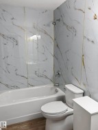 Contemporary bathroom featuring a white bathtub, polished chrome fixtures, and a toilet - 