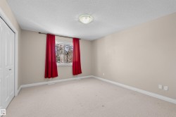 Bedroom featuring a window with natural light, light beige carpeting, white baseboards, and a flush-mount ceiling light fixture - 