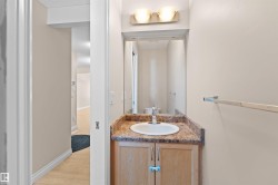 Bathroom vanity with a white oval sink set into a patterned countertop, light wood cabinetry, and a wall-mounted mirror - 