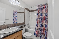 Bathroom featuring a wood-finish vanity with an integrated sink, a dark countertop, and a full-width mirror - 