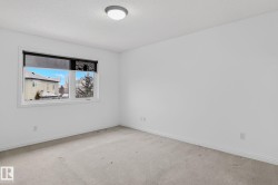 Neutral-toned room with light-colored carpeting, white baseboards, and a flush-mount ceiling light fixture - 