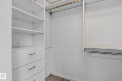Custom closet organization system featuring multiple adjustable shelves, integrated drawers with brushed nickel hardware, and dual hanging rods - 