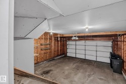 Single-car garage with a paneled overhead door, concrete flooring, and exposed wood framing - 