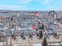 Residential neighborhood featuring detached homes with attached garages, multi-story apartment buildings, and distant tree lines - 