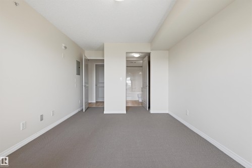 Carpeted interior room with light-colored walls and baseboards - 407 11453 Ellerslie Road Sw, Edmonton, AB - Indoor Photo Showing Other Room
