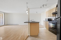 Open concept living area featuring wood-finish flooring and a kitchen island with an integrated sink - 