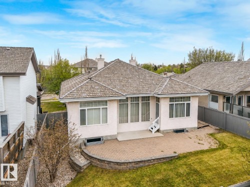 Rear exterior featuring a paver patio with a stone retaining wall, white siding, and multiple windows - 879 Drysdale Run Run, Edmonton, AB - Outdoor