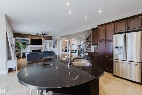 Kitchen island featuring a dark countertop with an undermount sink and gooseneck faucet - 3412 Macneil Link, Edmonton, AB 