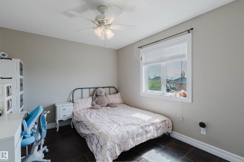 Room featuring a ceiling fan with integrated lighting, a white window frame with blinds, and dark tile flooring - 3412 Macneil Link, Edmonton, AB 