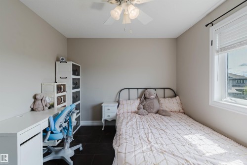 Neutral-toned room featuring dark tile flooring, a window with white blinds, and a ceiling fan with integrated lighting - 3412 Macneil Link, Edmonton, AB 