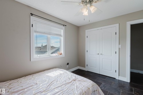 Room featuring dark rectangular floor tiles, a window with white blinds, and a ceiling fan with integrated lighting - 3412 Macneil Link, Edmonton, AB 