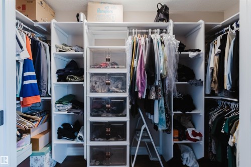 Custom closet system featuring white shelving and multiple hanging rods - 3412 Macneil Link, Edmonton, AB 