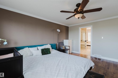 Bedroom featuring wood-finish flooring, a ceiling fan with integrated lighting, and crown molding - 3412 Macneil Link, Edmonton, AB 