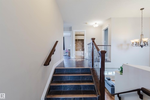 Staircase featuring dark tile treads with wood-finish risers and dark wood handrails - 3412 Macneil Link, Edmonton, AB 