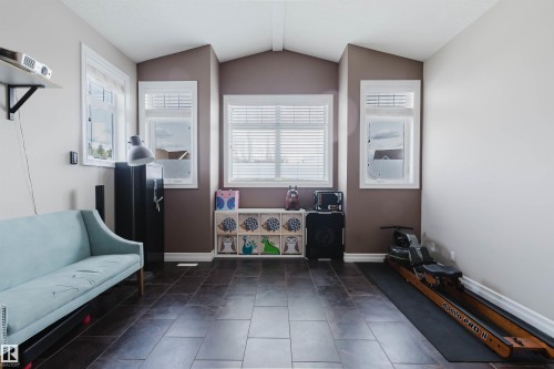 Spacious room featuring dark rectangular floor tiles, multiple windows with white blinds, and crisp white baseboards - 3412 Macneil Link, Edmonton, AB 