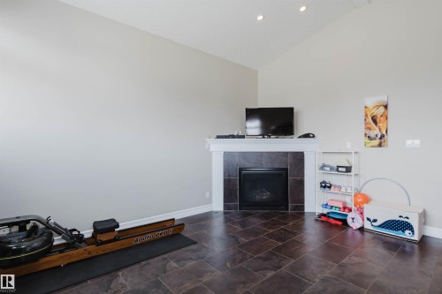 Vaulted ceilings complement a tiled fireplace with a white mantle - 3412 Macneil Link, Edmonton, AB 