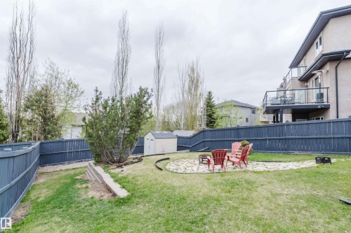 Expansive backyard featuring a stone patio area with a fire pit, a storage shed, and mature perimeter fencing - 3412 Macneil Link, Edmonton, AB 