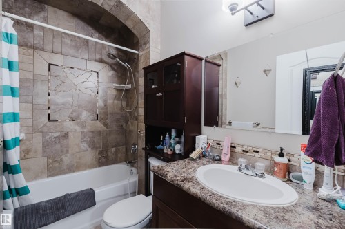 Bathroom featuring a tiled shower/tub combination with an arched surround and decorative accent tile - 3412 Macneil Link, Edmonton, AB 