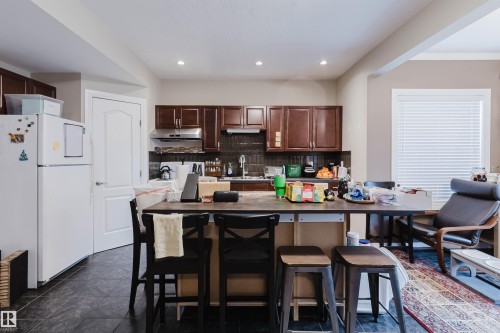 Kitchen featuring dark wood cabinetry, a dark tile backsplash, and recessed lighting - 3412 Macneil Link, Edmonton, AB 