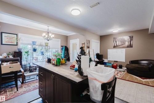Spacious interior featuring a large central island with storage, recessed lighting, crown molding, and multiple windows providing natural light - 3412 Macneil Link, Edmonton, AB 