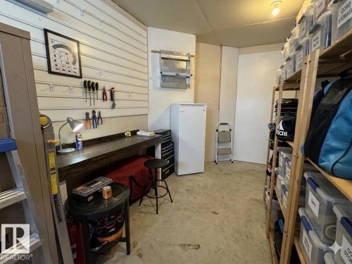 Organized utility room featuring a built-in workbench, wall-mounted storage system, freestanding refrigerator, and extensive shelving units - 3412 Macneil Link, Edmonton, AB - Indoor