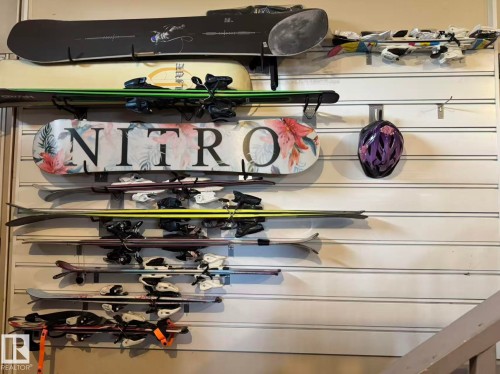White slatwall storage system with multiple horizontal tracks and various hook attachments, providing versatile organization - 3412 Macneil Link, Edmonton, AB - Indoor Photo Showing Other Room