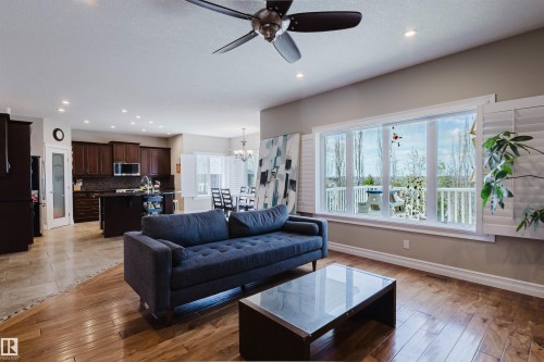 Spacious living area featuring polished wood-finish flooring and a ceiling fan with integrated lighting - 3412 Macneil Link, Edmonton, AB 