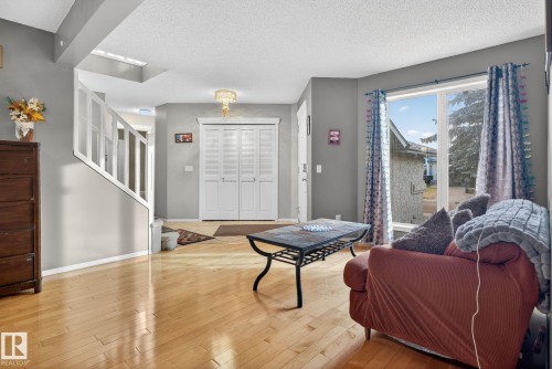 Spacious living area featuring light wood-finish flooring, a contemporary ceiling light fixture, and a large window - 3912 31 Street, Edmonton, AB 